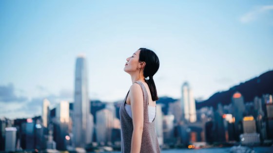 side-profile-of-young-asian-woman-taking-a-deep-breath-with-her-eyes-closed-enjoying-the-fresh-air-a